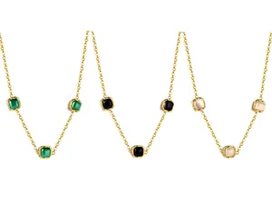 Detailed macro view of gold chain necklace featuring square emerald and opal pendants