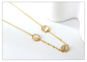 Close-up of golden chain necklace featuring three square cat eye stones with wavy edges