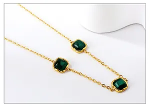 Detail of gold necklace featuring three square green gemstones with malachite texture