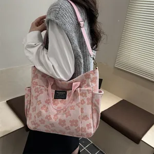 Pink floral canvas tote bag with fashion tag and adjustable strap shown on model