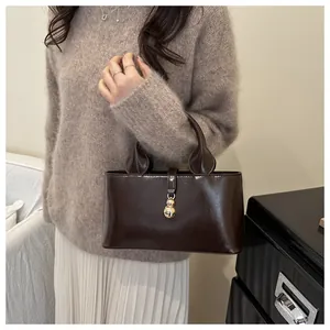Detail of dark brown patent leather handbag with gold spheres hardware on a chic background