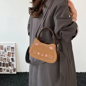 Sac bandoulière chat mignon en cuir PU marron porté par un mannequin en manteau gris