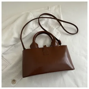 Detail of dark brown patent leather handbag with refined hardware and stylish handle