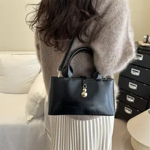 Elegant black patent leather handbag with gold bead detail and adjustable shoulder strap