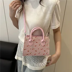 Pink tote bag with cherry print, featuring top handles and a detachable shoulder strap