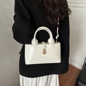 Elegant cream patent leather handbag with gold gourd pendant and adjustable strap