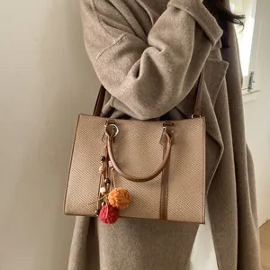 Retro brown tote bag with woven texture and colorful pom-pom charm on female model