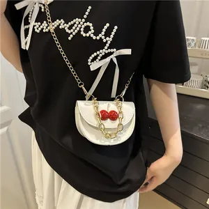 Mini white leather crossbody bag with red cherry charm and dual gold chain straps