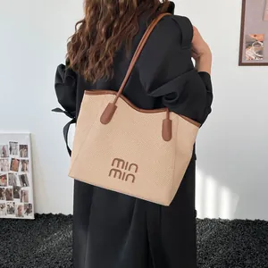Large vintage woven tote bag with brown leather straps and lettering on khaki straw