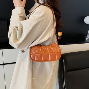 Chic orange quilted underarm bag in minimalist crescent shape with geometric stitching