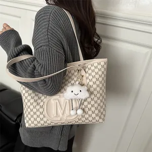 Large beige leather tote bag with brown M letter pattern and plush cloud pendant