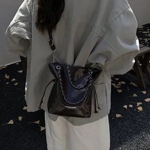Minimalist dark brown polished leather bucket bag with silver chain handle and shoulder strap