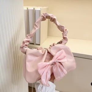 Détail du sac à main plissé rose avec un grand nœud en voile et anse froissée