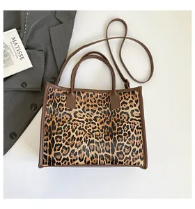 Detail view of leopard print tote bag with brown handles on a grey suit background