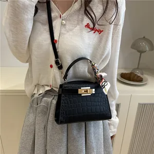 Black crocodile-patterned handbag with golden buckle and silk scarf on handle