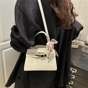 White crocodile pattern Kelly style handbag with a silk scarf on the top handle