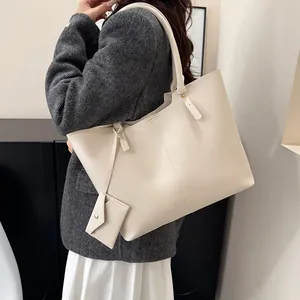 Minimalist cream tote bag with hanging pouch shown on model in modern home setting