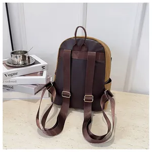 Detail view of the waterproof nylon backpack back showing adjustable brown straps and gold buckles