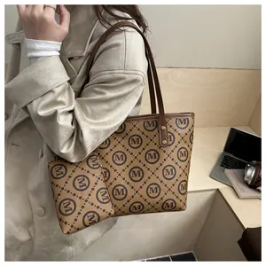 Brown faux leather tote bag with M monogram print and matching small zip pouch in use