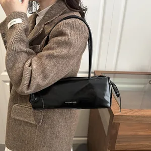 Sac sous le bras noir verni avec imprimé, porté avec un blazer marron à chevrons élégant