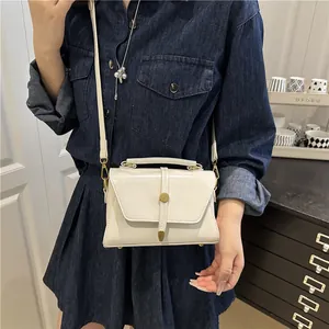 Borsa a tracolla minimalista bianco crema con fibbia dorata indossata da modella