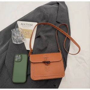 Close-up of retro orange-brown crossbody bag with toggle closure and white stitching detail