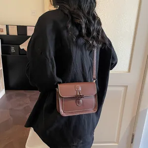 Vintage brown crossbody bag with horn buckle and contrast stitching on a black shirt