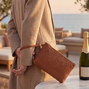 Detail of dark brown woven leather clutch featuring golden zipper and matching wrist strap