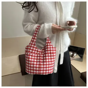 Détail du sac cabas à carreaux rouges et blancs porté par un mannequin en décor décontracté