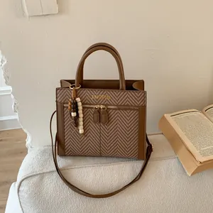 Detalle de bolso bandolera marrón de espiga con doble cremallera y adorno de cuentas