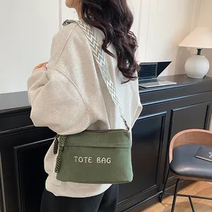 Dark green corduroy tote bag with embroidery and wide woven strap in a casual lifestyle setting