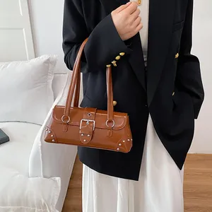 Braune Lackleder-Schultertasche mit silbernen Nieten und Schnallen am Modell gezeigt