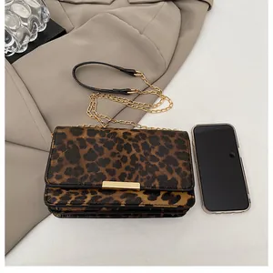 Detailed view of leopard print envelope bag with gold metal buckle and chain strap