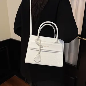 White crocodile embossed leather handbag for women featuring top handles and shoulder strap