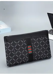 Detail of black leather clutch bag with green-red stripes and zip closure on office desk
