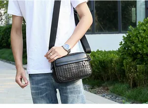 Photo en extérieur d'un sac bandoulière noir pour homme avec motif tressé à damier