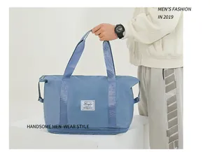 Detail of the expandable bottom compartment and logo on this gray-blue travel bag