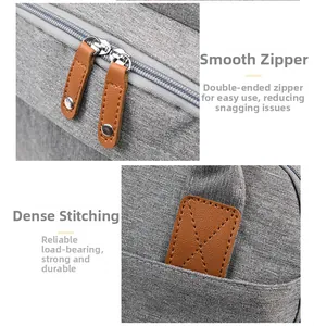 Close-up of smooth dual zippers and reinforced leather stitching on the gray diaper bag