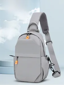 Detail of grey crossbody bag with USB port and orange zippers on a soft blue background
