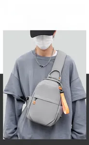 Close-up of grey crossbody chest bag with orange zipper detail and wide strap