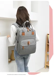 Detailed back view of a grey diaper backpack with brown texture leather accents and pockets