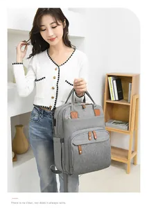 Detail view of a large grey multi-pocket diaper bag worn by a woman for travel