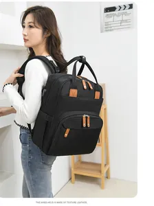 Detail of multi-functional black diaper backpack with premium leather handles on model