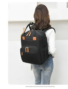 Macro detail of high-capacity black mommy backpack with brown leather trim and metal zippers