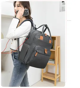 Detail of dark grey diaper bag showing external USB charging port and brown leather accents
