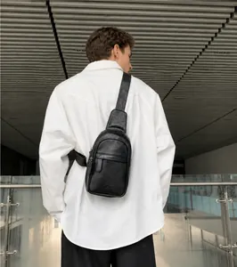 Detail showing the adjustable leather strap and textured PU material of the black sling bag