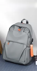 Detail view of grey minimalist backpack featuring vibrant orange zipper and textured fabric