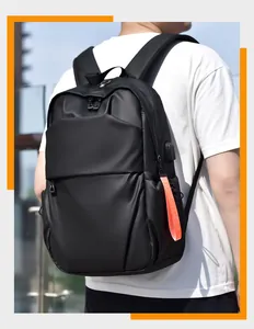 Detail of minimalist black backpack with USB charging port and orange strap on side