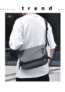 Photo en extérieur d'un sac messager gris avec rabat et bandoulière rembourrée confortable