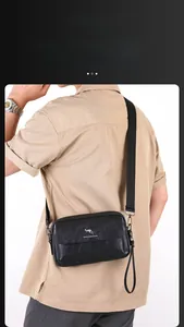 Detail of a black leather crossbody bag for men with adjustable straps and logo engraving